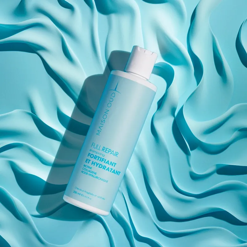 Flacon de soin cosmétique mis en scène sur un drapé turquoise